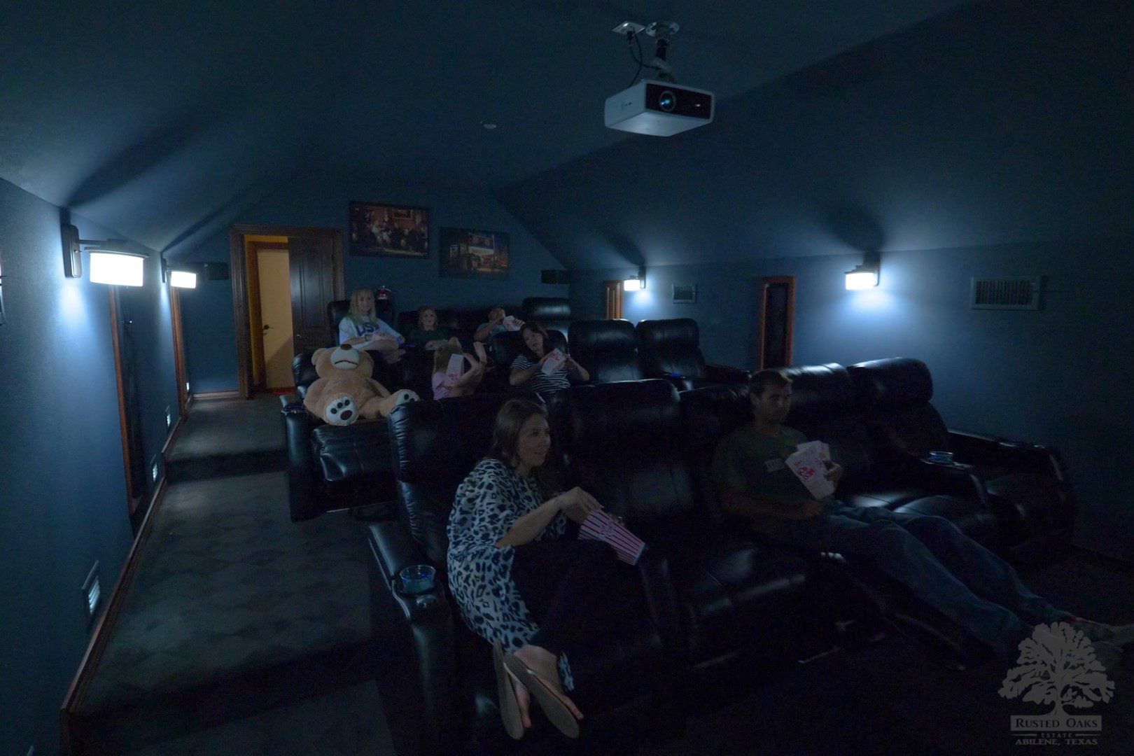 Family watching a movie in the private theater at Rusted Oaks Estate